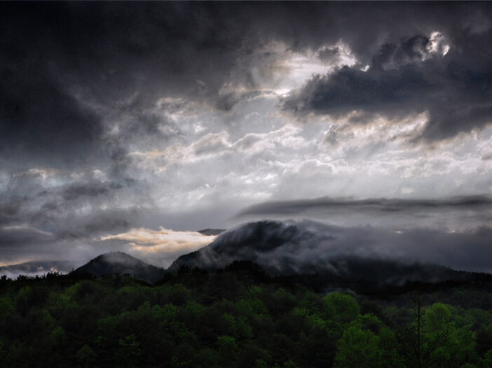 A dark and brooding sky with clouds sweeping over a mountain top taken from artist Sally J Smith's studio.