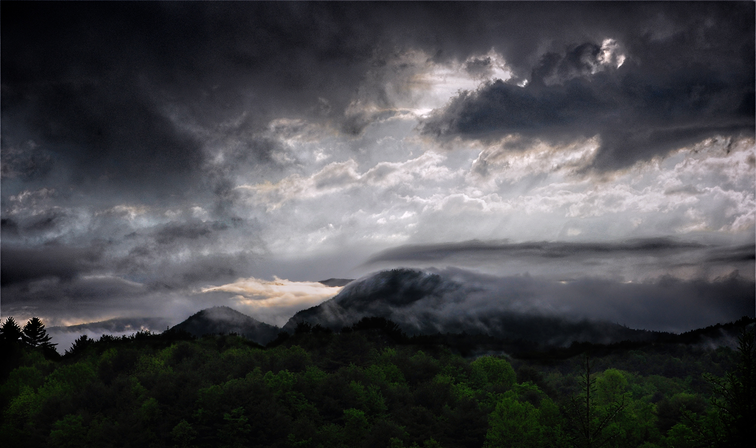 A dark and brooding sky with clouds sweeping over a mountain top taken from artist Sally J Smith's studio.